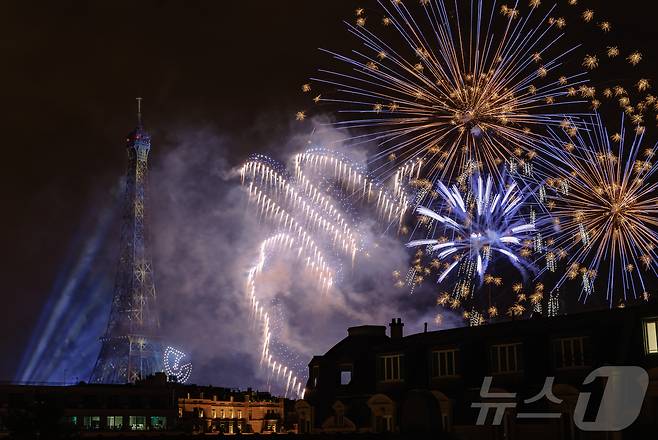 14일(현지시간) 프랑스 혁명 기념일(바스티유 데이)을 기념하기 위해 에펠탑에 펼쳐진 불꽃놀이 쇼에서 1천100대의 드론이 불꽃과 함께 빛의 향연을 펼치고 있다. 2024.7.15/뉴스1 ⓒ News1 이준성 기자