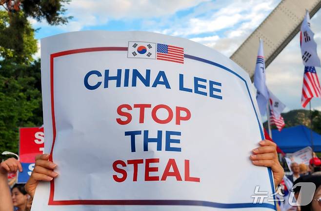 15일 오후 서울대 정문 앞에서 열린 모스 탄 교수의 특별강연 참석한 한 시민이 'CHINA LEE, STOP THE STEAL(차이나 리, 스탑더 스틸)'라는 문구가 적힌 손팻말을 들고 있다.