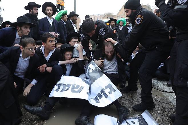 지난해 3월18일(현지시각) 이스라엘 예루살렘에서 초정통파 유대교 신도들이 징집 반대 시위에 나서 도로를 점거하자 경찰들이 이들을 해산하고 있다. 당시 이스라엘 대법원은 그동안 군입대가 면제되어 온 초정통파 유대교 신도들의 징집의 법적 타당성을 논의했다. 예루살렘/EPA 연합뉴스