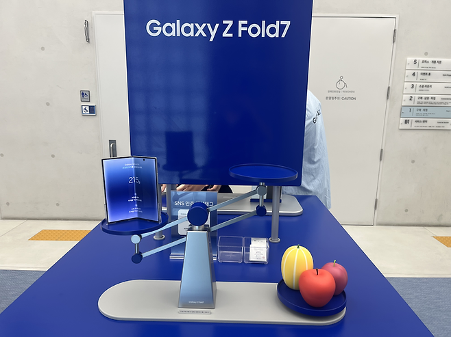 갤럭시 Z폴드7 존에는 실제와 동일한 무게의 사과 모형과 전자저울이 함께 비치돼 있어 관람객들이 직접 무게를 비교해볼 수 있다. [사진=안서진 기자]