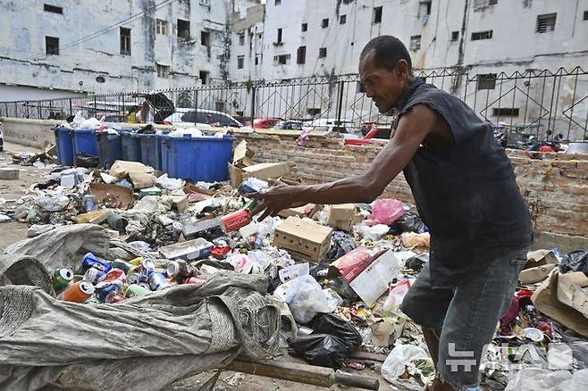 [아바나=AP/뉴시스] 15일(현지 시간) 쿠바 아바나에서 한 남성이 쓰레기 더미에서 재활용할 알루미늄 깡통을 수거하고 있다. 2025.07.16.