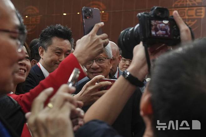 [베이징=AP/뉴시스] 젠슨 황 엔비디아 최고경영자(CEO)가 16일(현지 시간) 중국 베이징에서 열린 제3회 중국 국제 공급망 촉진 박람회 개막식에서 참석자들로부터 셀카 요청을 받고 있다. 2025.07.16.