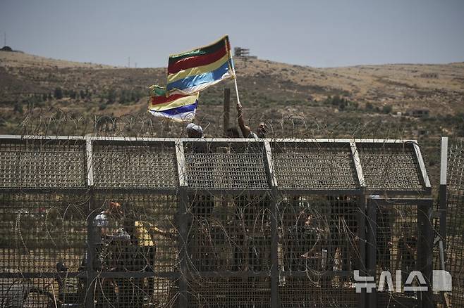 [마즈달샴스=AP/뉴시스] 16일 골란고원 아래 시리아-이스라엘 접경에서 이스라엘과 친한 드루즈계가 깃발을 흔들고 있다. 건너 시리아 남서단 수웨이다에서 시리아 정부군과 드루즈계 간 충돌이 이어지고 있고 거기에 이스라엘이 가세하고 있다. 2025.07.16.