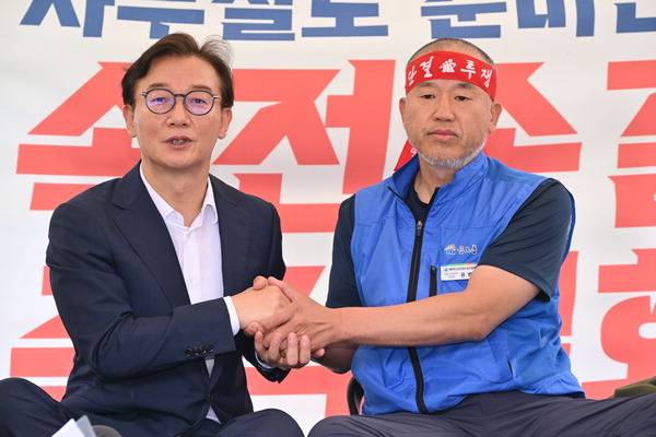 전재수 해양수산부 장관 후보자가 17일 서울 국회 앞에서 해수부 부산 이전을 반대하며 단식 투쟁 중인 윤병철 공무원노조 해수부지부 위원장과 만나 손을 잡고 있다. 윤 위원장은 이날 전 후보자를 만나 단식 투쟁 중단을 선언했다.  김정록 기자