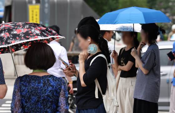 Locals are battling heat with sun umbreallas and handheld fans in Seoul on July 3, 2025 [NEWS1]