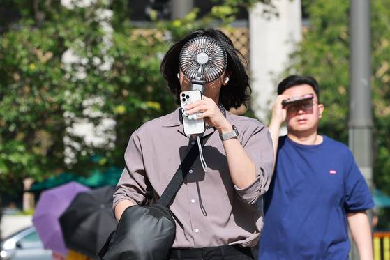 People walk the streets in Jongno District, central Seoul, in record heat waves that hit Seoul last week, on July 10. [YONHAP]