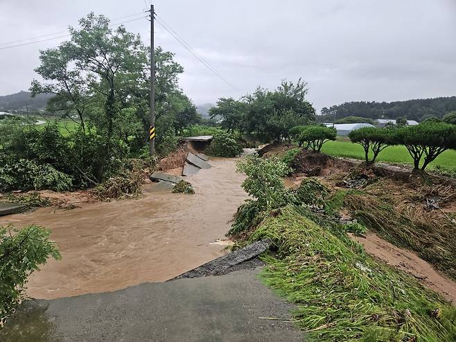 17일 오전 충남 태안에 200㎜ 넘는 물폭탄이 쏟아진 가운데 태안군 태안읍 상옥리 소하천 주변 도로가 불어난 물에 휩쓸려 무너져 내렸다. 연합뉴스