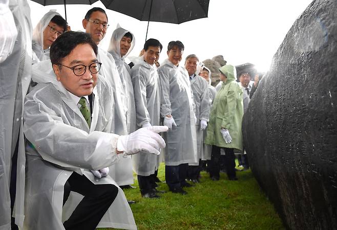 우원식 국회의장이 제헌절인 17일 오전 서울 여의도 국회 잔디광장에서 열린 국회 상징석 제막식에서 참석자들과 함께 상징석을 살펴보고 있다. 상징석에는 국회가 민주주의의 보루로서 ‘12·3 비상계엄’ 해제를 이끌었다는 내용의 문구가 새겨져 있다.  [국회사진기자단]