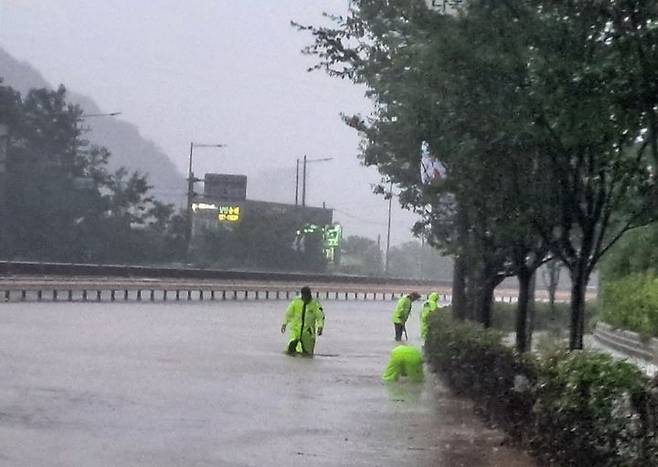[광주=뉴시스] 17일 오후 6시께 광주 동부경찰서 직원들이 동구다목적체육관 인근 도로에 막힌 배수로를 맨손으로 뚫고 있다. (사진 = 동부경찰서 제공) 2025.07.17. photo@newsis.com *재판매 및 DB 금지