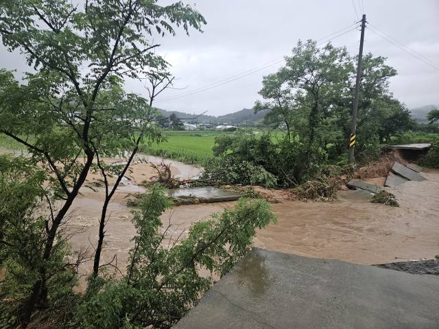 17일 오전 충남 태안에 200㎜ 넘는 물폭탄이 쏟아진 가운데 태안군 태안읍 상옥리 소하천 주변 도로가 불어난 물에 휩쓸려 무너져 내렸다. 연합뉴스