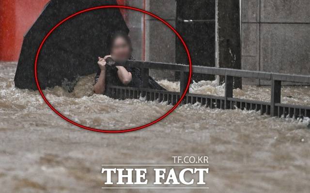 17일 하루 동안에만 400mm가 넘는 폭우가 내린 광주에서 한 시민이 북구청 앞 도로에서 물살에 휩쓸려 난간을 붙잡아 버티고 있다. /뉴시스
