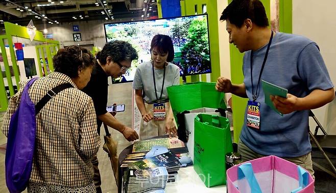 무주군 홍보 부스를 찾은 관람객들에게&nbsp; 반딧불축제 응모권&nbsp; 이벤트 참여 방법을 설명하고 있다.