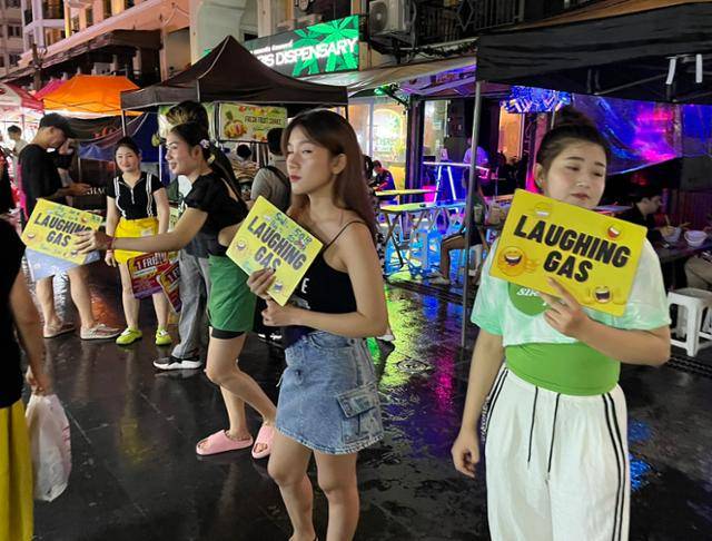 지난해 7월 '배낭여행객의 성지'로 불리는 태국 방콕 카오산로드에서 가게 점원들이 '웃음 가스'라고 적힌 팻말을 들고 호객 행위를 하고 있다. 방콕=허경주 특파원