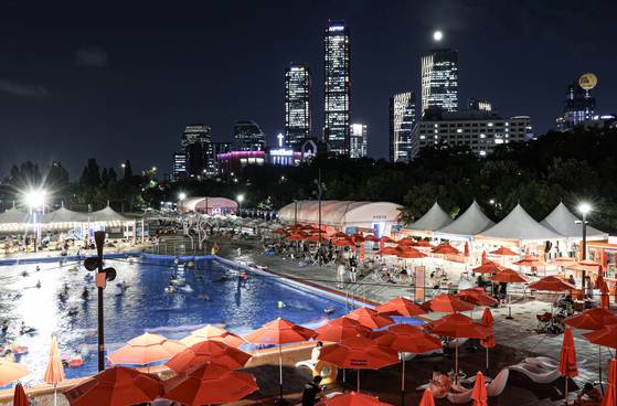 한강 수영장 6곳이 지난달 20일 일제히 문을 열었다. 올해는 야간 개장을 전면 도입한 것이 큰 특징이다. 여의도 수영장의 야경. 파크원 단지와 관광용 기구 ‘서울달’ 등 여의도를 상징하는 여러 랜드마크에 수영장이 둘러싸여 있다. 김경록 기자