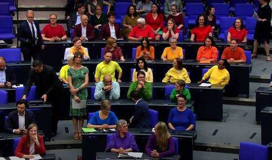 독일의 녹색당과 좌파당 소속 의원들이 지난달 26일 연방하원 본회의장에서 빨강, 주황, 노랑 등 무지개 색의 티셔츠를 입고 율리아 클뢰크너 연방하원 의장에게 항의하고 있다. [사진 독일 ntv 캡처]