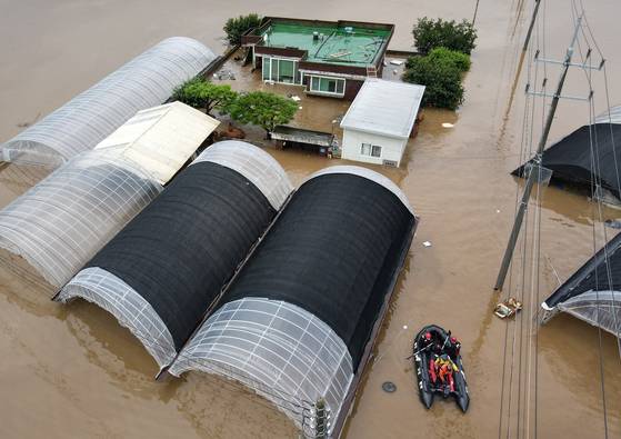 Rescue workers from the Chungcheong-Gangwon 119 Special Rescue Team under the National 119 Rescue Headquarters evacuate a resident by boat in Yesan County, South Chungcheong, on the morning of July 17 following record rainfall in the region. [NEWS1]