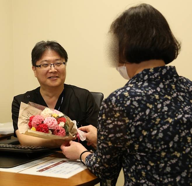 50대 말기 신부전 환자가 고도 감작으로 재이식이 어려운 힘든 상황을 이겨내고 두 번째 신장이식 수술로 건강을 되찾다. 사진은 정병하 서울성모병원 신장내과 교수에게 뜨개질로 만든 카네이션 꽃다발을 전하고 있는 모습. 제공=서울성모병원
