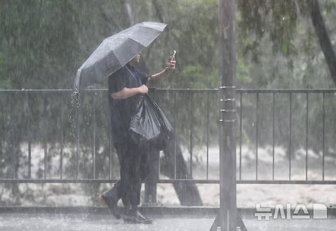 [광주=뉴시스] 박기웅 기자 = 호우경보가 내려진 17일 오후 광주 동구 호남동 광주교 일대 광주천 강물이 범람 수위까지 도달, 한 시민이 휴대전화로 불어난 강물을 촬영하고 있다. 2025.07.17. pboxer@newsis.com