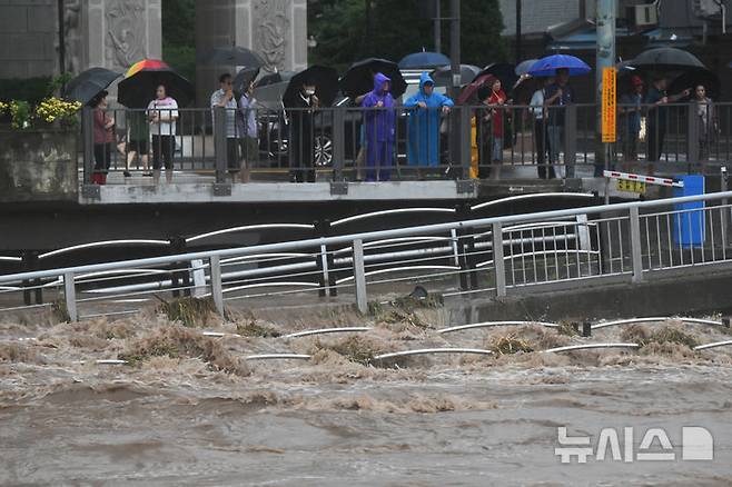 [광주=뉴시스] 박기웅 기자 = 17일 오후 광주 서구 양동복개상가 인근 태평교 밑으로 흐르는 광주천 강물이 범람 수위까지 도달한 가운데 시민들이 불어난 강물을 바라보고 있다. 이날 태평교는 범람 우려로 주민 대피령이 내려졌다. 2025.07.17. pboxer@newsis.com