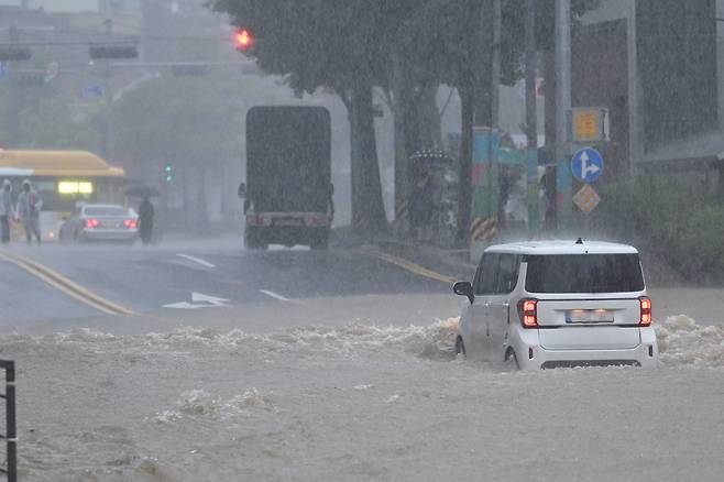 광주지역에 하루 최고 311㎜ 폭우가 쏟아진 17일 오후 침수된 광주 북구청 앞 도로 위로 한 차량이 지나가고 있다. 뉴시스