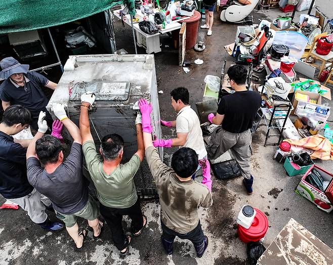 18일 전날 내린 폭우로 침수 피해를 본 대구 북구 노곡동 한 가정집에서 주민과 공무원들이 복구 작업을 하고 있다. 연합뉴스