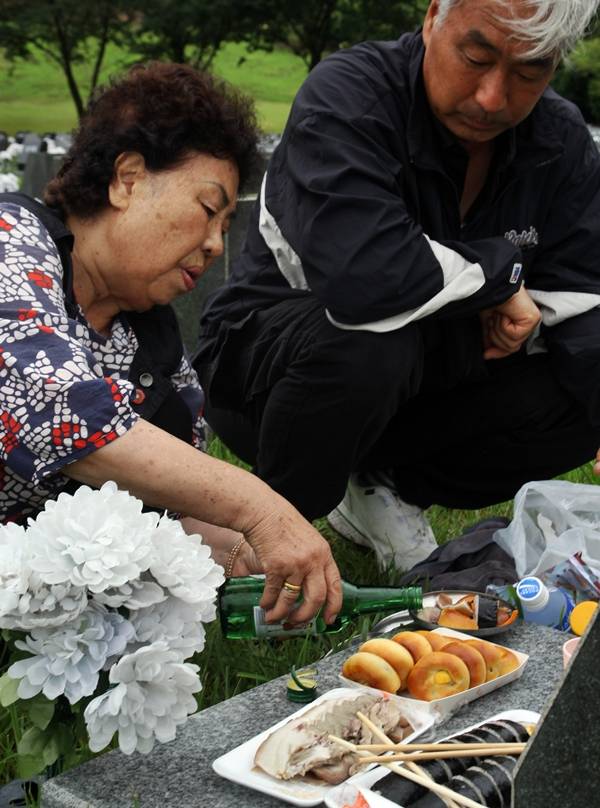 오옥순 씨가 아들과 함께 아버지 표석을 찾아 술잔을 올리고 있다. ⓒ제주의소리