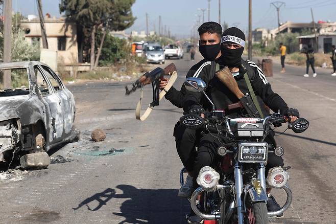 18일 시리아 남부 스웨이다주 알두르 마을에서 총을 든 베두인족 무장대원이 오토바이를 타고 있다./AFP 연합뉴스
