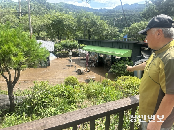20일 오후 가평군 조종면에서 10년째 펜션을 운영해 온 박상욱(73)씨가 불어난 강물에 책상과 의자가 진흙에 반쯤 잠긴 마당을 가리키고 있다. 2025.7.20 /목은수기자wood@kyeongin.com