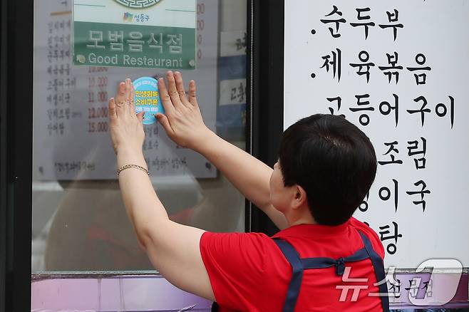 서울 성동구의 한 가게에서 '민생회복 소비쿠폰 사용 가능 매장' 스티커를 부착하고 있다. (성동구 제공) 2025.7.17/뉴스1