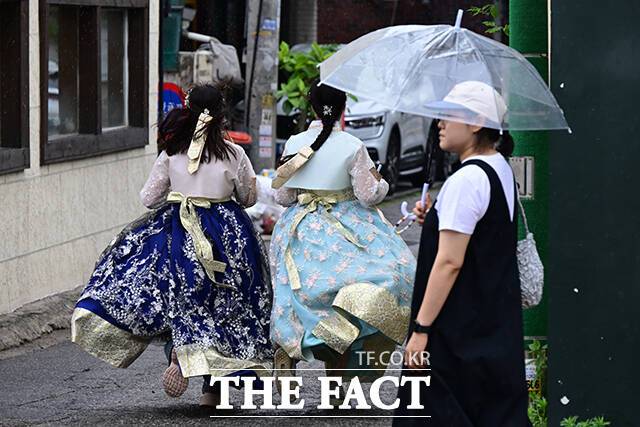 민생회복 소비쿠폰 외국인 대상자는 건강보험이나 의료보험에 가입돼 있다는 전제하에 내국인이 주민등록표에 1인 이상 포함되거나, 한국인과 결혼했거나, 영주권자이거나, 난민인정자인 경우만 해당한다. 사진은 지난 13일 오후 서울 종로구 창성동 거리에서 한복을 입 외국인들이 빗방울을 피해 거리를 달리는 모습. /남윤호 기자