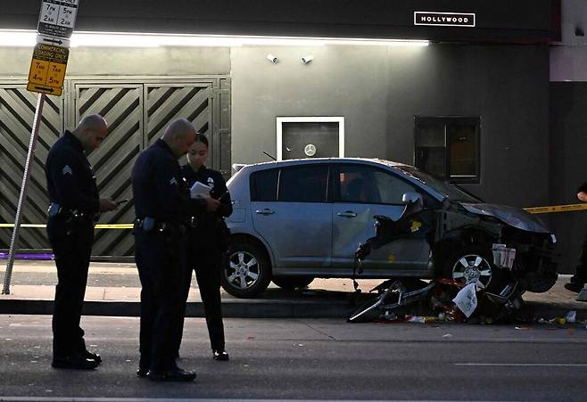 19일 새벽 로스앤젤레스 이스트할리우드에서 차량이 인파를 향해 돌진한 현장에서 경찰관들이 사고 차량 곁에 서 있다. AFP연합뉴스
