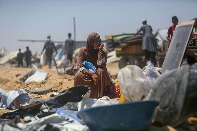 2025년 7월11일 이스라엘의 공격으로 파괴된 팔레스타인 땅 가자지구 남부 칸유니스의 피란민촌에서 한 여성이 망연한 표정으로 앉아 있다. AFP 연합뉴스