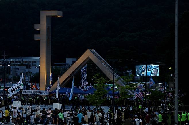 ‘샤’ 자 형태의 서울대 정문에 불을 밝힌 채 ‘사기꾼 모스 탄 방한 반대 대학생 긴급행동’(아래쪽)이 교문 앞에서 특강을 하는 탄 교수를 규탄하고 있다.