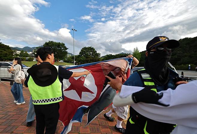 모스 탄 교수 방한 환영 집회 참석자들이 ‘모스 탄 방한 반대 대학생 긴급행동’이 주최한 기자회견장 인근에서 북한 인공기를 찢고 있다.