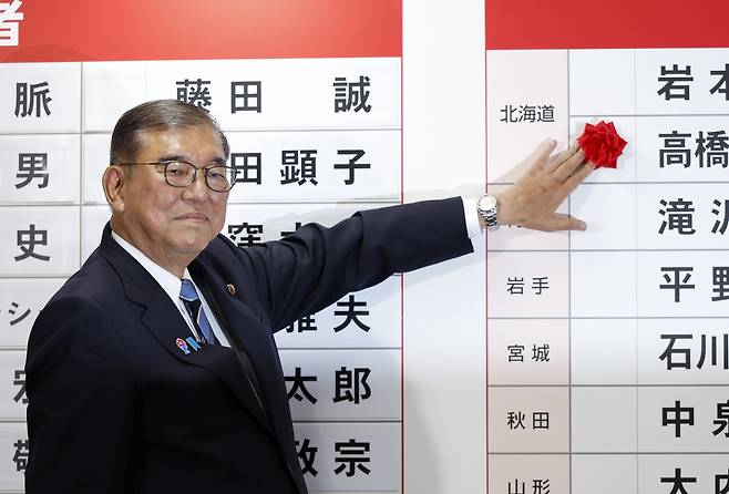 이시바 시게루 일본 총리가 20일 일요일 도쿄의 자민당 본부에서 당선된 후보의 이름 위에 붉은 종이 장미를 올려놓고 있다. AP연합뉴스