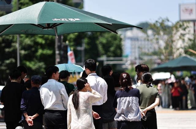 서울 세종로 사거리에서 시민들이 햇빛 가림막 아래에서 신호를 기다리고 있다. 연합뉴스