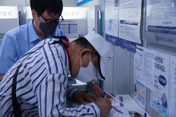 민생회복 소비쿠폰 1차 신청 첫날일 오늘(21일) 인천 동구의 한 은행에서 시민이 소비쿠폰을 신청하고 있다. [사진 = 이장원 기자]