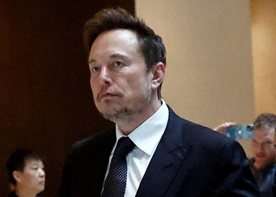 FILE PHOTO: Tesla Chief Executive Officer Elon Musk walks next to Tesla's Senior Vice President Tom Zhu and Vice President Grace Tao as he leaves a hotel in Beijing, China May 31, 2023. REUTERS/Tingshu Wang/File Photo