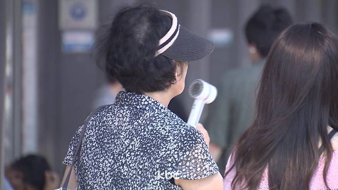▲ 무더위에 휴대용 선풍기를 쐬고 있는 시민&nbsp;
