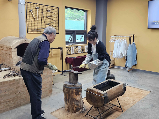 A participant in last year's ironmaking camp gets hands-on experience using a hammer and anvil. (National Research Institute of Cultural Heritage)