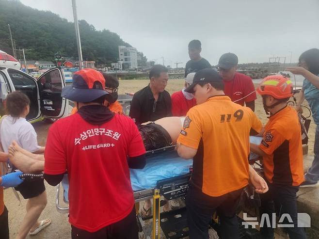[영덕=뉴시스] 안병철 기자 = 지난 19일 오후 경북 영덕 하저해수욕장에서 구조요원이 심정지에 빠진 중국인 관광객을 심폐소생술로 생명을 구한 뒤 119구급대에 인계하고 있다.(사진=영덕군 제공) 2025.07.21. photo@newsis.com