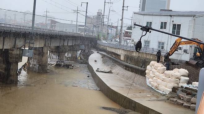 18일 오후 광주 신안 북구 신안교에서 현장 인부들이 중장비를 동원해 폭우로 무너진 제방에 대한 응급 복구공사를 하고 있다. ⓒ시사저널 정성환