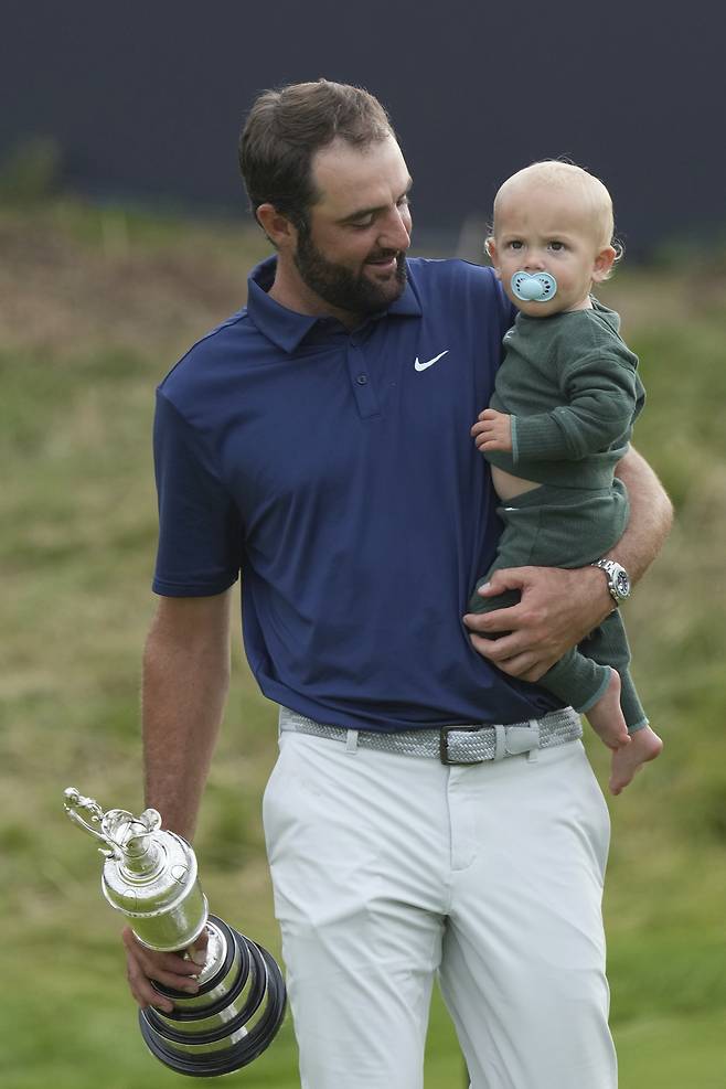 스코티 셰플러가 21일 영국 북아일랜드 포트러시의 로열포트러시gc에서 열린 제153회 디 오픈을 제패한뒤 순은제 트로피 클라레저그를 들고 아들 베넷을 안은 채 기쁨을 누리고 있다.  포트러시｜AP연합뉴스