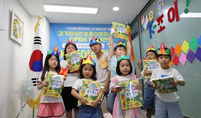 딱지치기 이벤트에 참가한 어린이들 (서울=연합뉴스) '화성반송 종이문화교육원' 설립 기념 이벤트로 진행된 딱지치기에 참가한 어린이들이 상품으로 받은 종이접기 교재를 들고 기념 사진을 찍고 있다. [종이문화재단 제공]