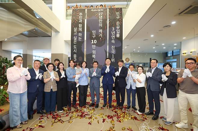 지난 21일 대구 중구청 1층 로비에서 전입신고로 10만 번째 주민이 된 정병모·이연희 부부(왼쪽에서 7번째)에게 류규하 중구청장(가운데)과 직원들이 축하를 보내고 있다. /대구 중구 제공