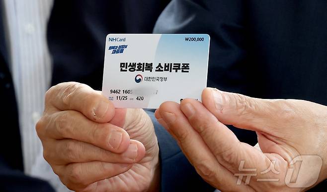 구윤철 경제부총리 겸 기획재정부 장관이 21일 오후 민생회복 소비쿠폰 시행 첫날 충남 공주시 산성시장을 방문 과일가게등 재래시장 소비쿠폰 사용을 점검하며 소비쿠폰으로 과일을 구매하러 나온 시민의 카드를 들어 보이고 있다. 2025.7.21/뉴스1 ⓒ News1 김기남 기자