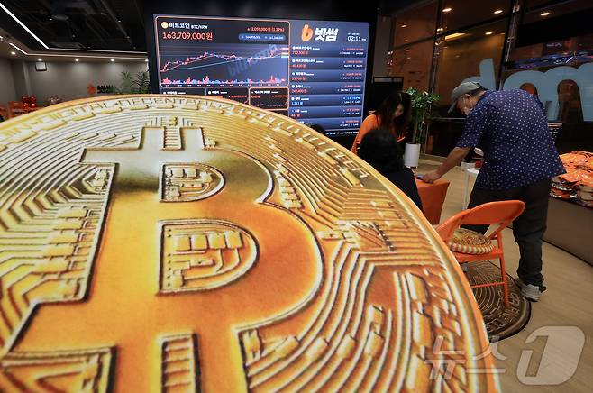 18일 오후 서울 강남구 서초구 빗썸라운지 강남본점에서 비트코인 모형이 놓인 바닥에 코인 시세 그래프가 비치는 모습. 2025.7.18/뉴스1 ⓒ News1 김진환 기자