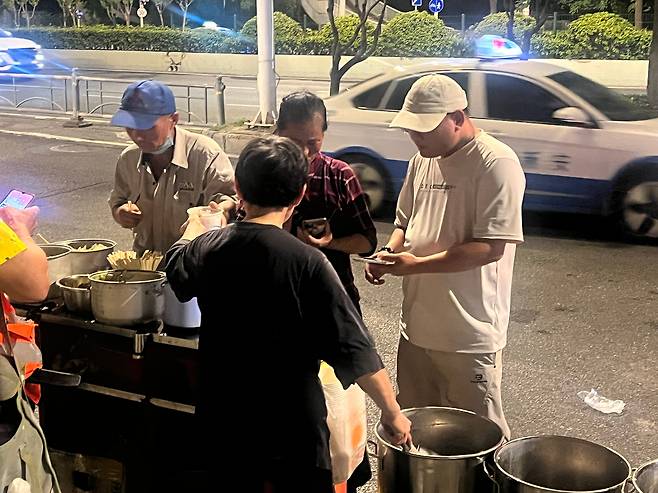 지난 17일 새벽 중국 우한의 택시 기사들이 인력 시장 옆에서 파는 값싼 죽으로 끼니를 때우고 있다./우한=이벌찬 특파원
