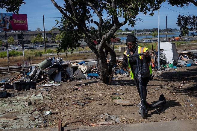 미국 캘리포니아주 오클랜드 노숙자 캠프에서 생활하는 한 여성이 2025년 5월 오클랜드 시에서 해당 지역을 청소하는 동안 소지품을 꺼내고 있다. /연합뉴스