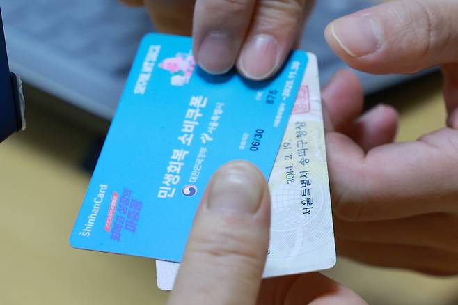 민생회복 소비쿠폰 신청이 시작된 지난 21일 서울 송파구 거여2동주민센터에서 시민이 신청한 소비쿠폰을 받고 있다. [사진 = 연합뉴스]